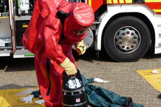 Eine Person steht in einem Schutzanzug vor einem ABC-Fahrzeug
