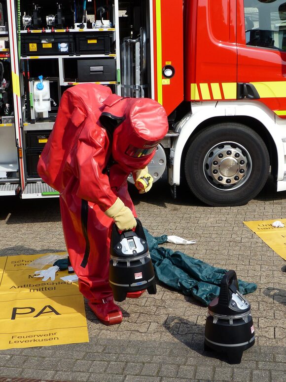 Eine Person steht in einem Schutzanzug vor einem ABC-Fahrzeug