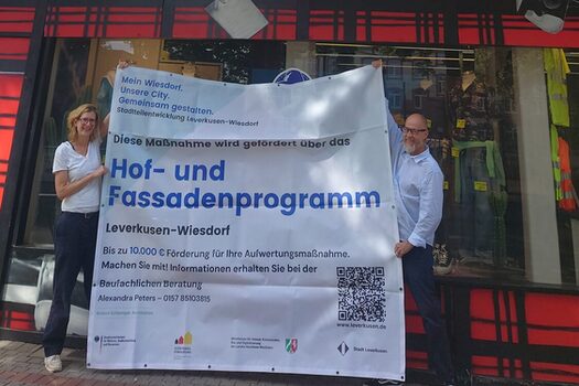 Silke de Roode vom Büro Stadt- und Regionalplanung Dr. Jansen und Geschäftsführer Guido Niggemann vor einer Fassade, die mit Mitteln aus dem Hof- und Fassadenprogramm umgestaltet wird