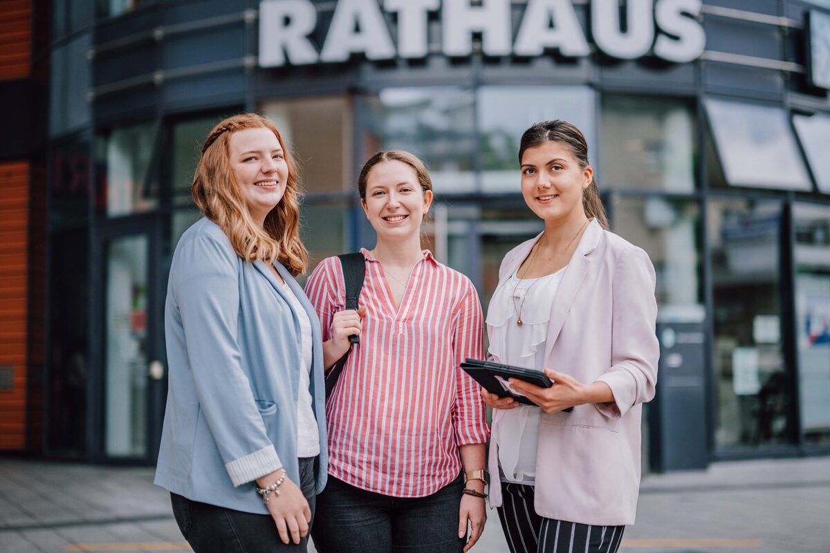 Drei Auszubildende vor dem Rathaus