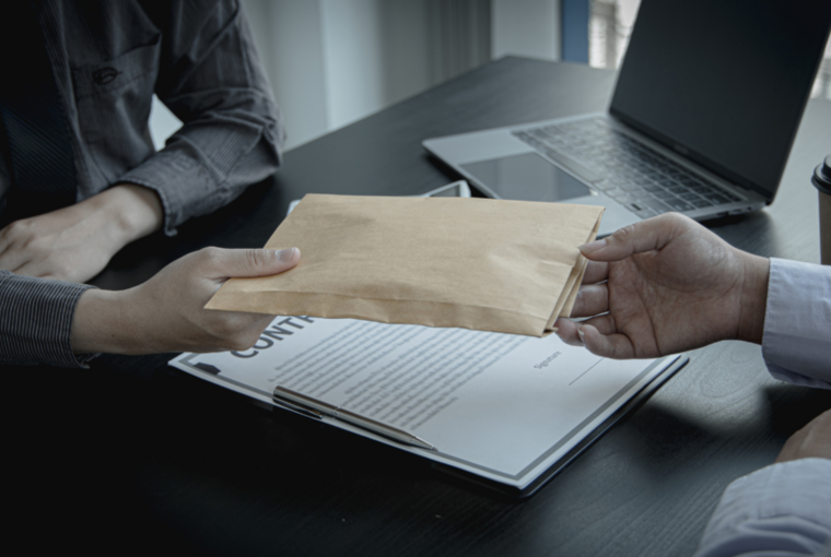 Eine Hand gibt einer anderen Hand einen geschlossenen Umschlag