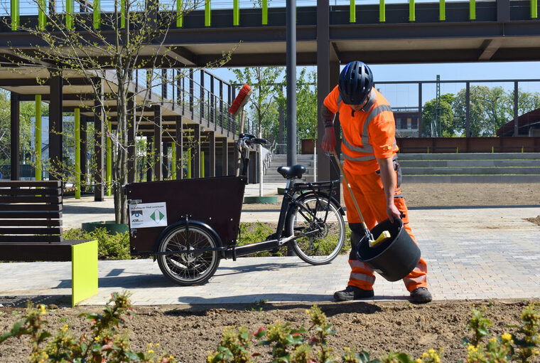 Ein Mitarbeiter des Job Services sammelt Müll im Brückenpark Opladen ein