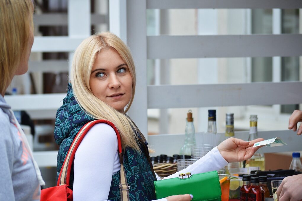 Eine Frau kauft etwas an einem Stand und bezahlt es