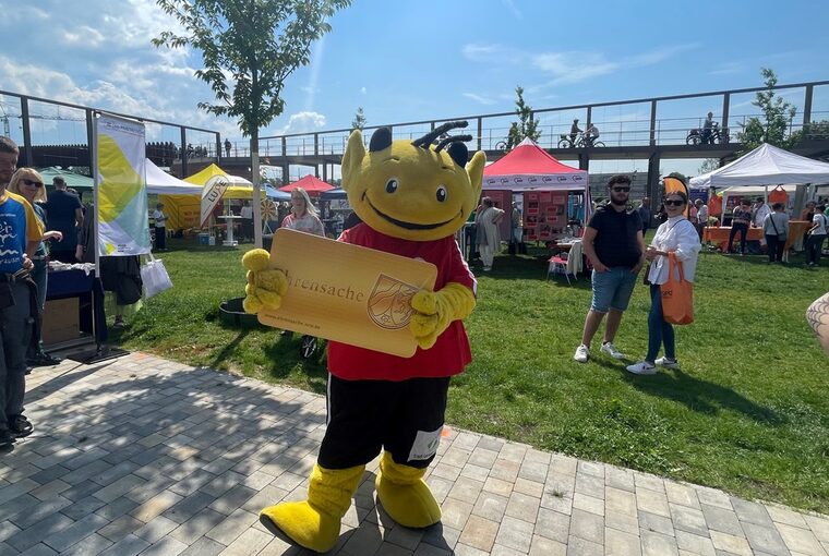 Maskottchen "Ehrenamtsteufel" hält die Ehrenamtskarte in den Händen