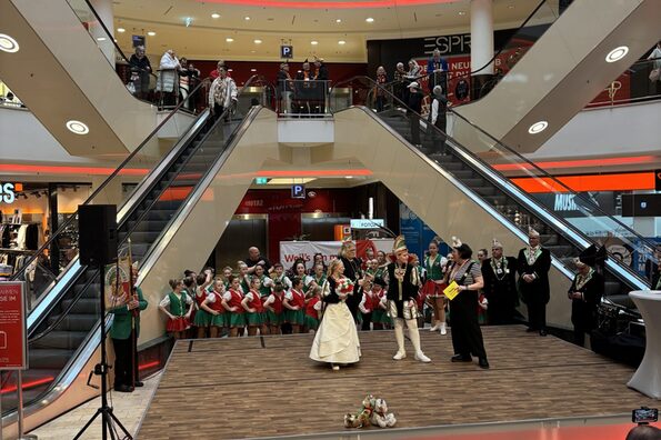 Eine Kindertanzgruppe und drei Personen stehen auf einer Bühne