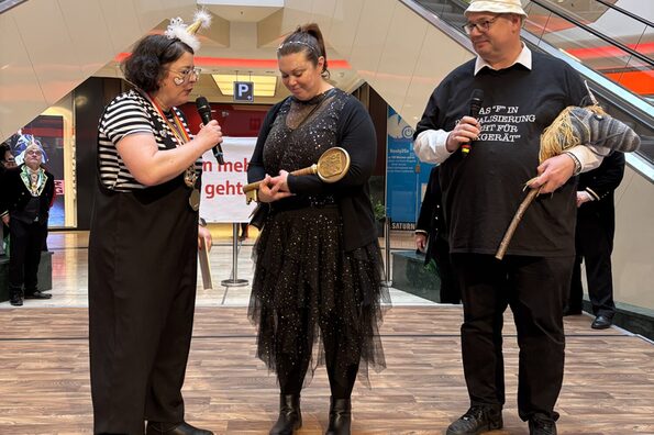 Stefan Hebbel hält ein Steckenpferd und steht neben zwei Personen auf der Bühne