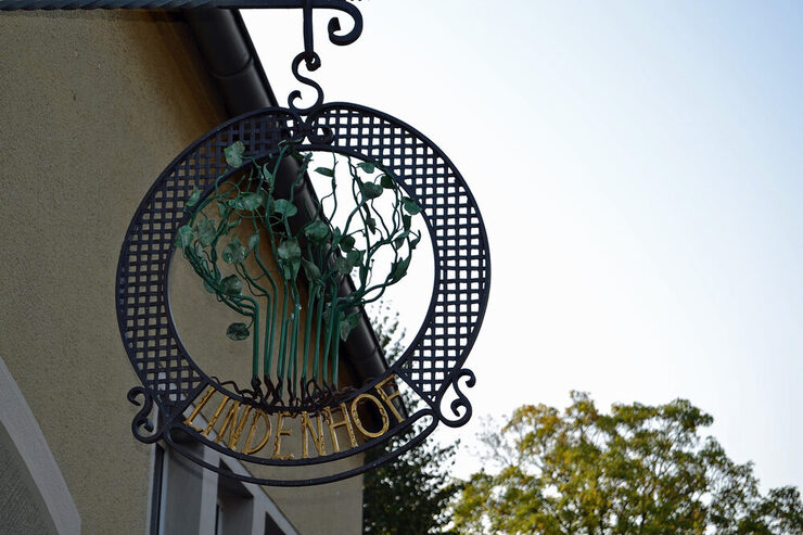 Das runde, geschmiedete Emblem des "Lindenhofs" hängt am Gebäude.