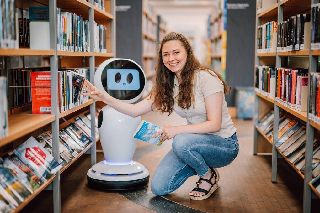 Weibliche Person nimmt Buch aus einem Bücherregal