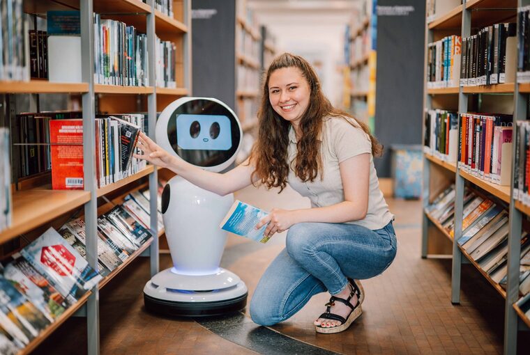 Weibliche Person nimmt Buch aus einem Bücherregal