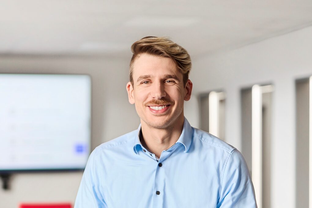 Ein junger Mann sitzt in einem Besprechungsraum auf einem Tisch