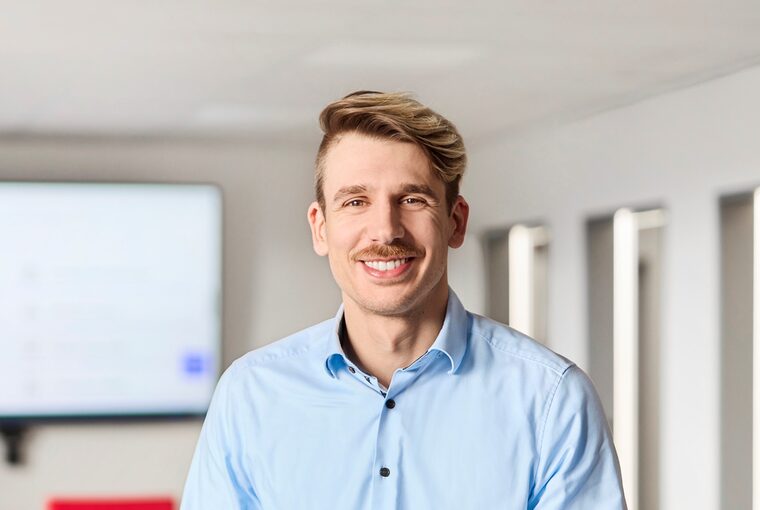 Ein junger Mann sitzt in einem Besprechungsraum auf einem Tisch