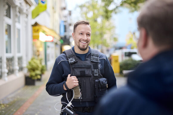 Ein Mitarbeiter des Ordnungsamts Leverkusen redet mit einer anderen Person und lächelt