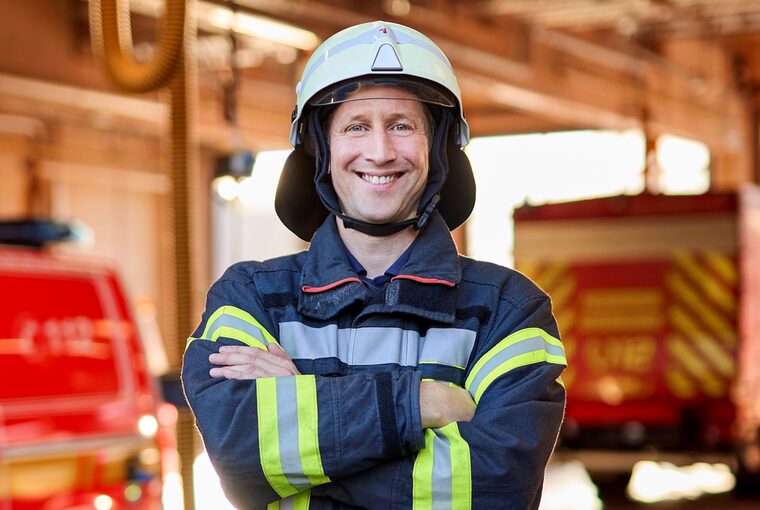 Ein Feuerwehrmann steht in der Halle, wo die Feuerwehrautos stehen