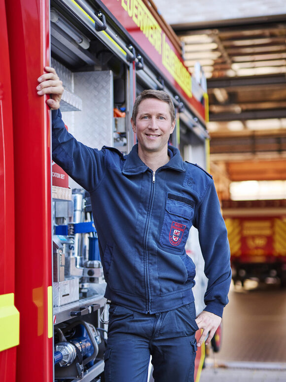 Ein Feuerwehrmann lehnt an einem Einsatzfahrzeug