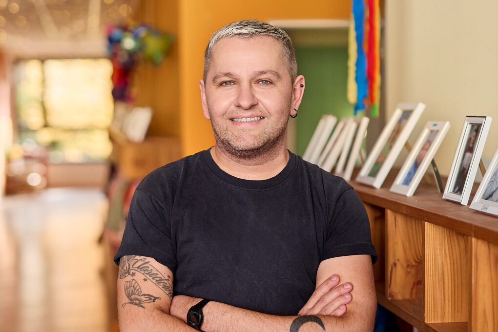 Eine junger Mann steht in einer Kita auf dem Flur