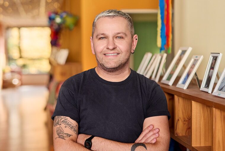 Eine junger Mann steht in einer Kita auf dem Flur