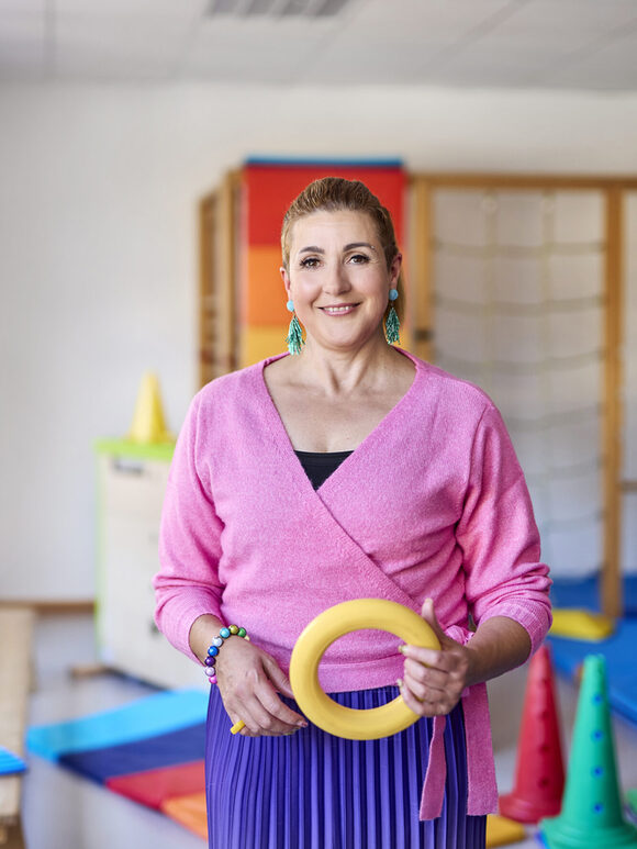 Eine Kita Mitarbeiterin hält Spielzeug in der Hand und lächelt