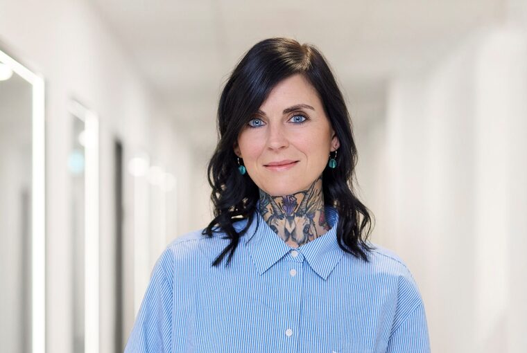 Eine Frau steht im Flur und hält ein Tablet in der Hand