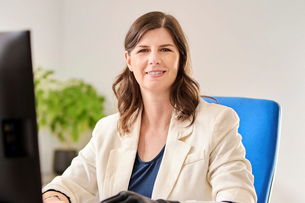 Eine junge Frau sitzt am Schreibtisch und arbeitet, die trägt eine Handprothese