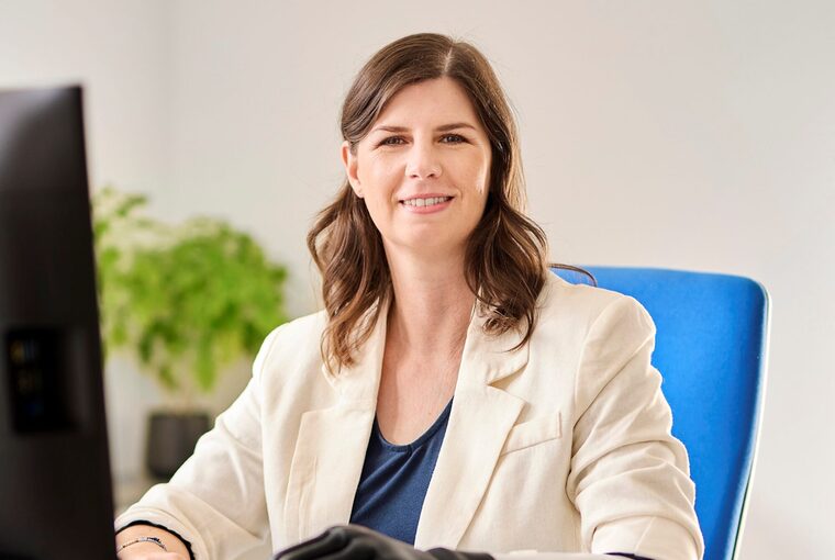 Eine junge Frau sitzt am Schreibtisch und arbeitet, die trägt eine Handprothese