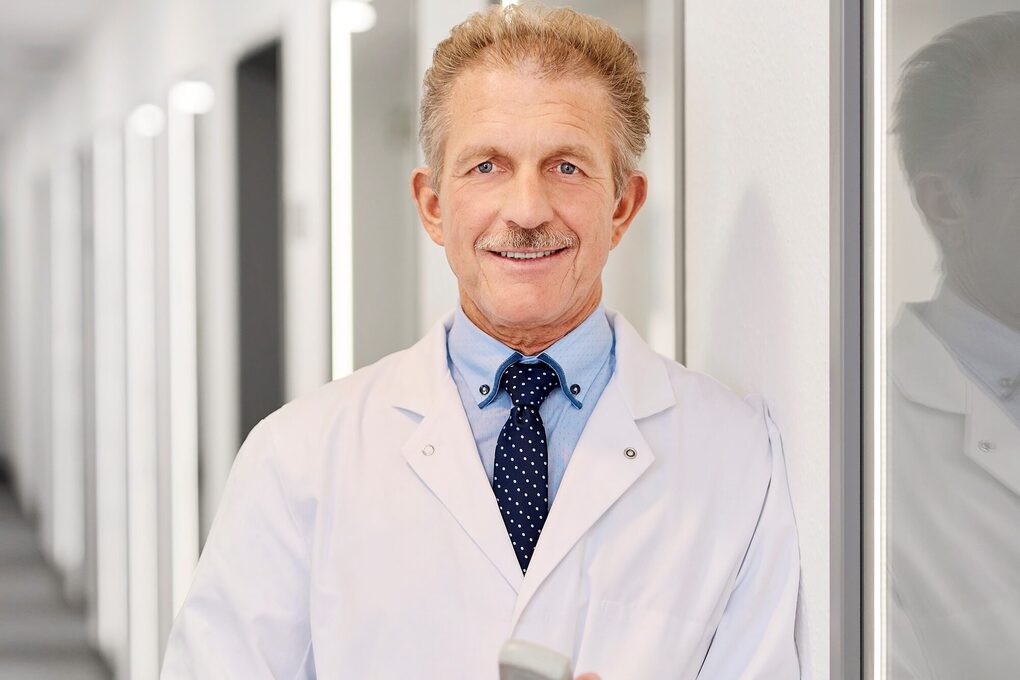 Ein Mann mit Kittel steht auf dem Flur