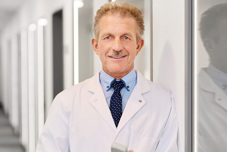 Ein Mann mit Kittel steht auf dem Flur