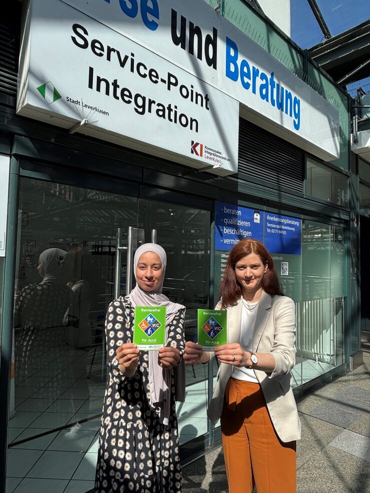 Zwei Personen stehen mit dem Gütesiegel Barrierefrei vor dem Service-Point Integration Leverkusen