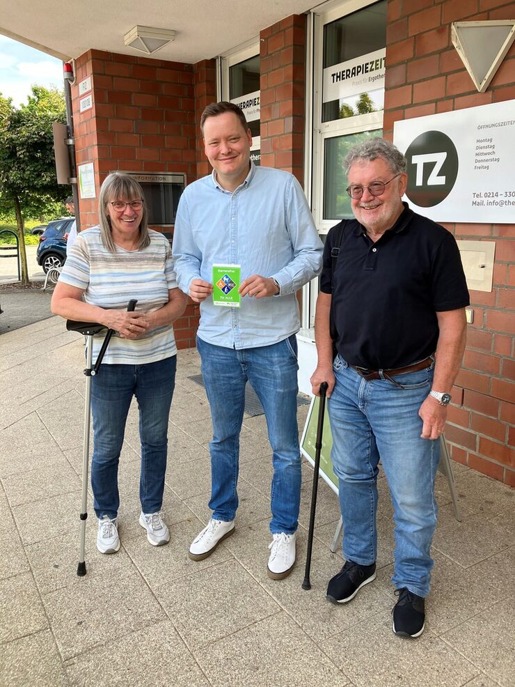 Drei Personen stehen vor der Therapiezeit in Leverkusen mit Barrierefrei-Siegel in der Hand