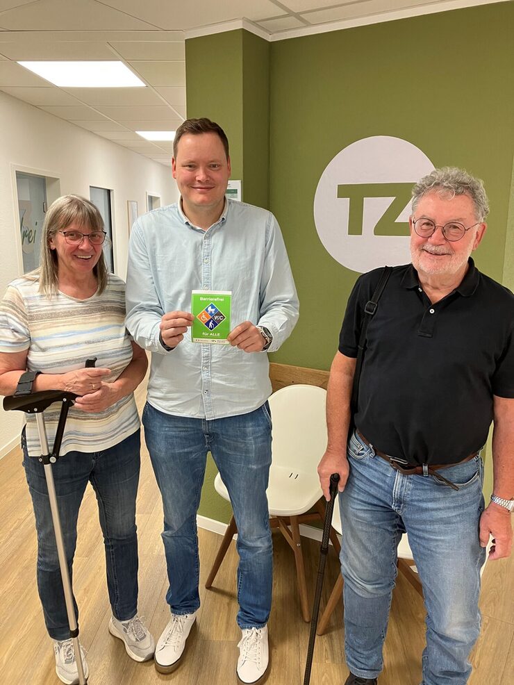 Drei Personen stehen vor der Therapiezeit in Leverkusen mit Barrierefrei-Siegel in der Hand